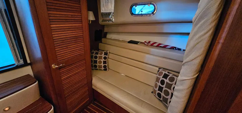 Sunbeam Yacht Photos Pics 2002 Pursuit 3800 Express cabin with beige seating, wooden accents, and decorative pillows.