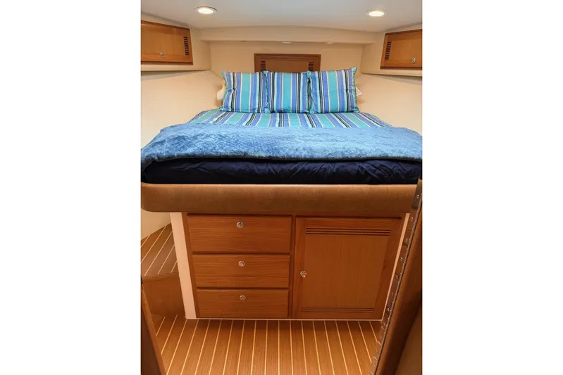 Kraken Yacht Photos Pics Cozy cabin interior of 2007 Cabo Express with striped bedding and wooden storage.