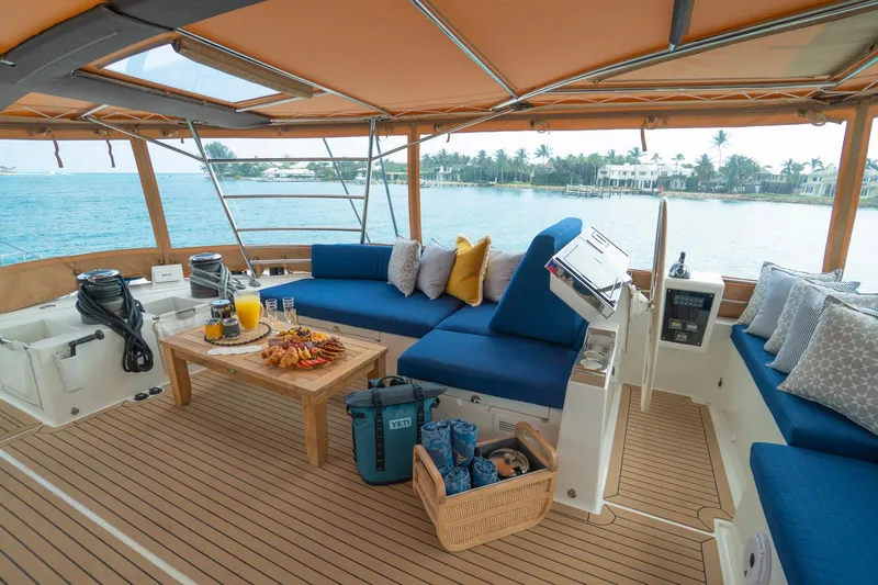 Andromeda Yacht Photos Pics Luxurious Lagoon 620 yacht interior with blue seating, wooden table, and ocean view.
