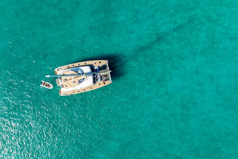 Andromeda Yacht Photos Pics Aerial view of 2016 Lagoon 620 catamaran on clear turquoise water.