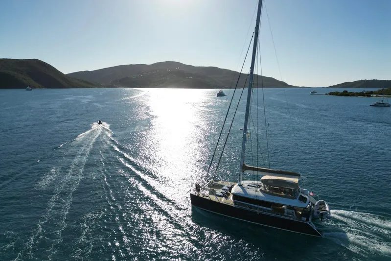 Andromeda Yacht Photos Pics Lagoon 620 catamaran sailing in sunny waters, 2016 model, with scenic mountain backdrop.
