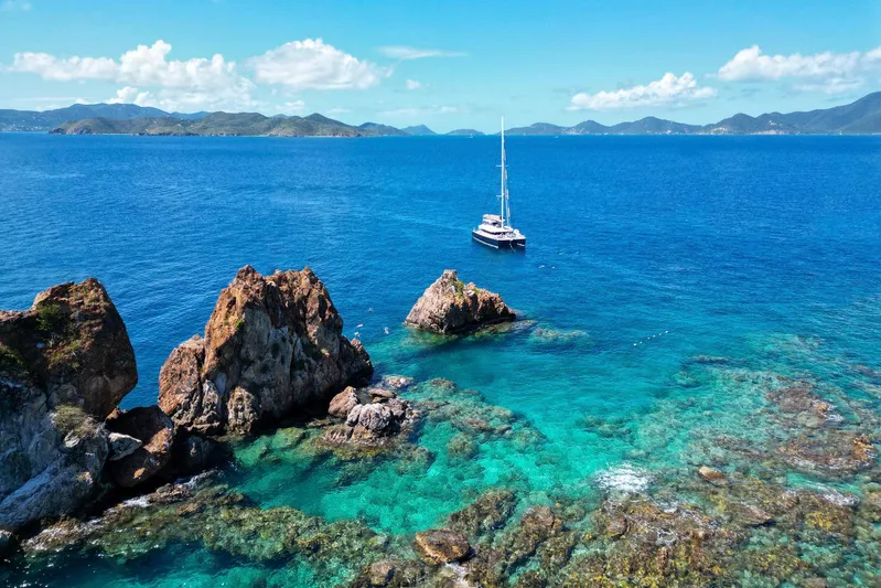 Andromeda Yacht Photos Pics Lagoon 620 yacht sailing near rocky coastline in clear blue waters, 2016 model.