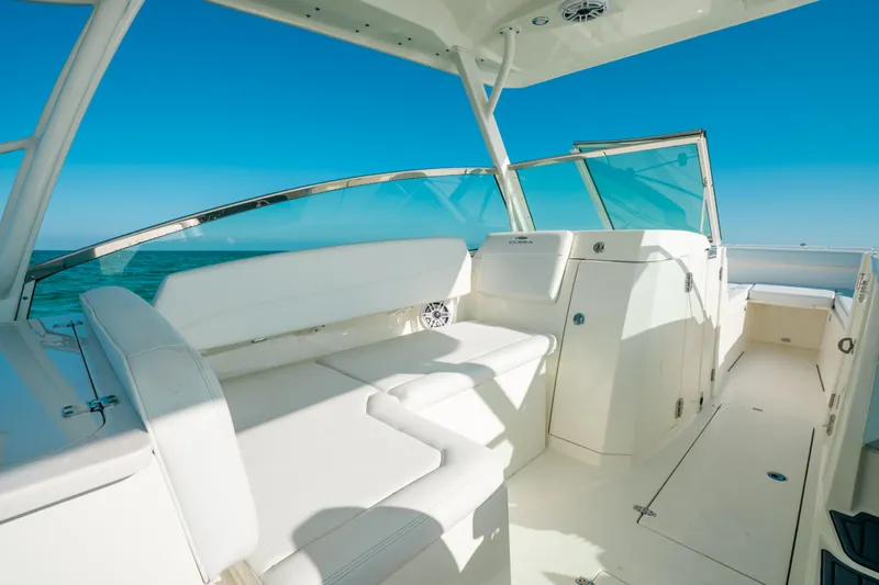 + Sea Keeper 2 Yacht Photos Pics 2024 Cobia 330 Dual Console boat interior with white seating and clear blue sky.