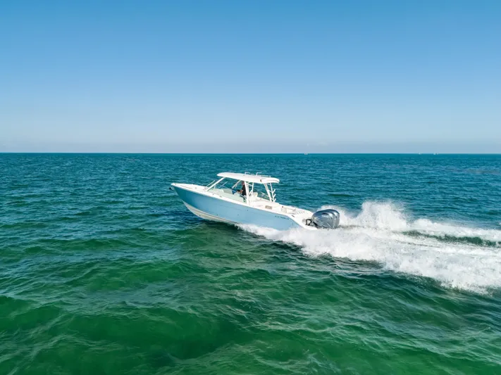 + Sea Keeper 2 Yacht Photos Pics 2024 Cobia 330 Dual Console boat cruising on open sea under clear blue sky.