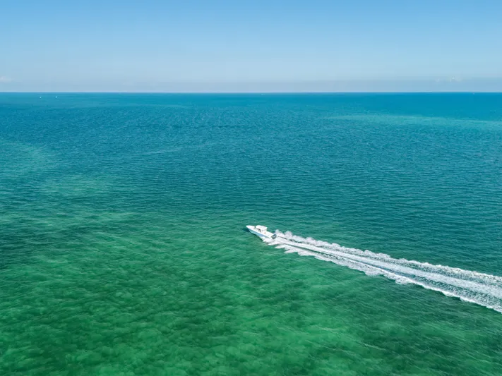 + Sea Keeper 2 Yacht Photos Pics Aerial view of 2024 Cobia 330 Dual Console speeding across turquoise ocean waters.