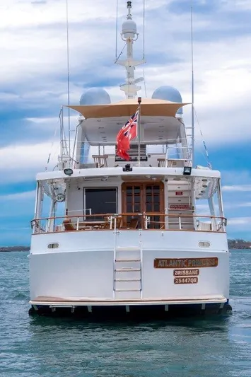 Atlantic Princess Yacht Photos Pics Custom GeTa 86ft Motor Yacht, 1992, on water, rear view with flag, under cloudy sky.