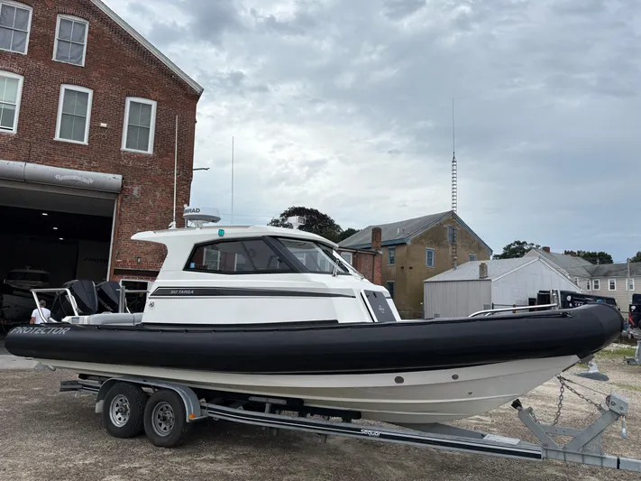  Yacht Photos Pics 2020 Protector 310 Targa boat on trailer, parked near brick building.