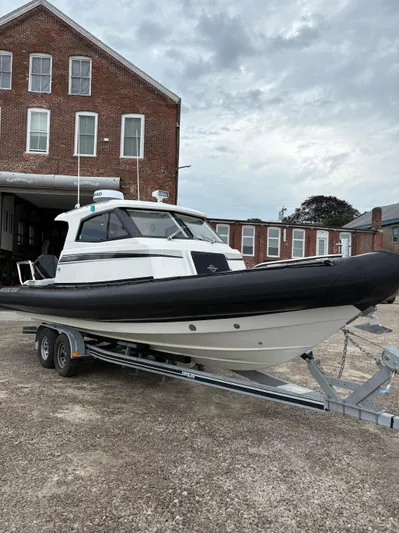  Yacht Photos Pics 2020 Protector 310 Targa boat on trailer, parked outside brick building.
