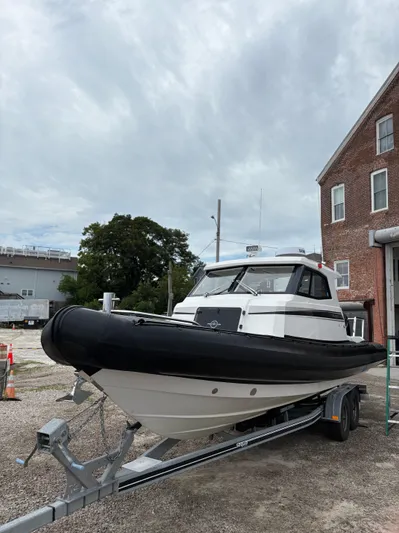  Yacht Photos Pics 2020 Protector 310 Targa boat on trailer, parked near a brick building.