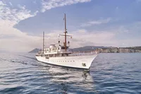 Vintage 1902 Ailsa Shipbuilding yacht cruising on calm sea under a partly cloudy sky.