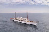 Historic 1902 Ailsa Shipbuilding vessel sailing on calm ocean under partly cloudy sky.