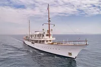 Vintage 1902 Ailsa Shipbuilding yacht cruising on open sea under cloudy sky.