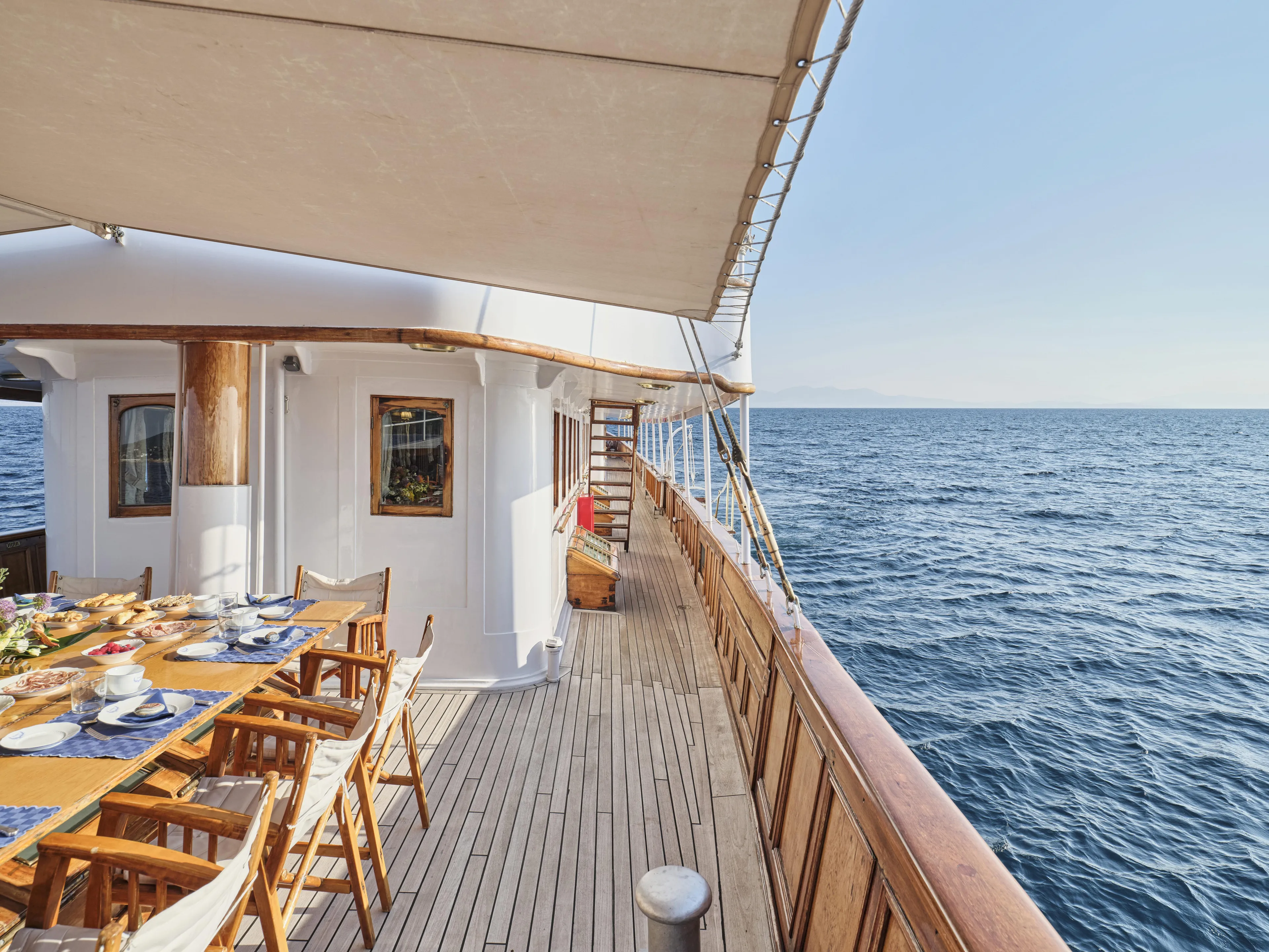 Luxurious 1902 Ailsa Shipbuilding yacht deck with dining area, overlooking the serene ocean.