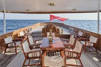 Luxurious 1902 Ailsa Shipbuilding yacht deck with wooden furniture and ocean view.