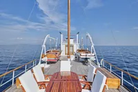 Luxurious 1902 Ailsa Shipbuilding yacht deck with wooden furniture, surrounded by calm ocean waters.
