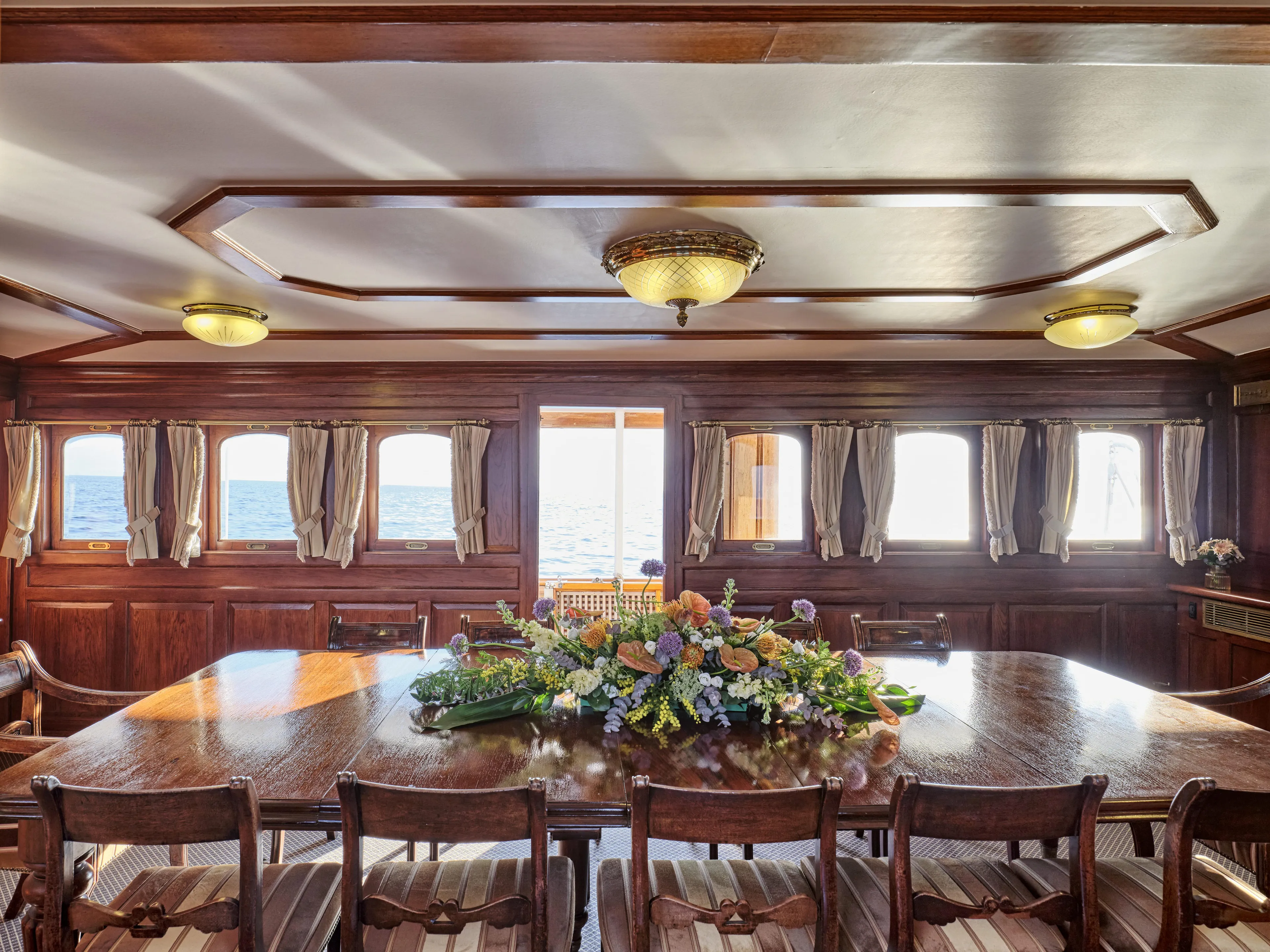 Luxurious vintage ship dining room with wooden decor and floral centerpiece, Ailsa Shipbuilding, 1902.