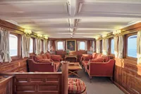 Luxurious vintage ship interior with elegant wood paneling and plush red seating, Ailsa Shipbuilding, 1902.
