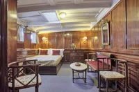 Luxurious vintage ship cabin with wooden paneling, elegant furniture, and soft lighting, built in 1902.