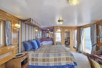 Luxurious ship cabin interior with elegant decor, blue accents, and ocean view, Ailsa Shipbuilding, 1902.