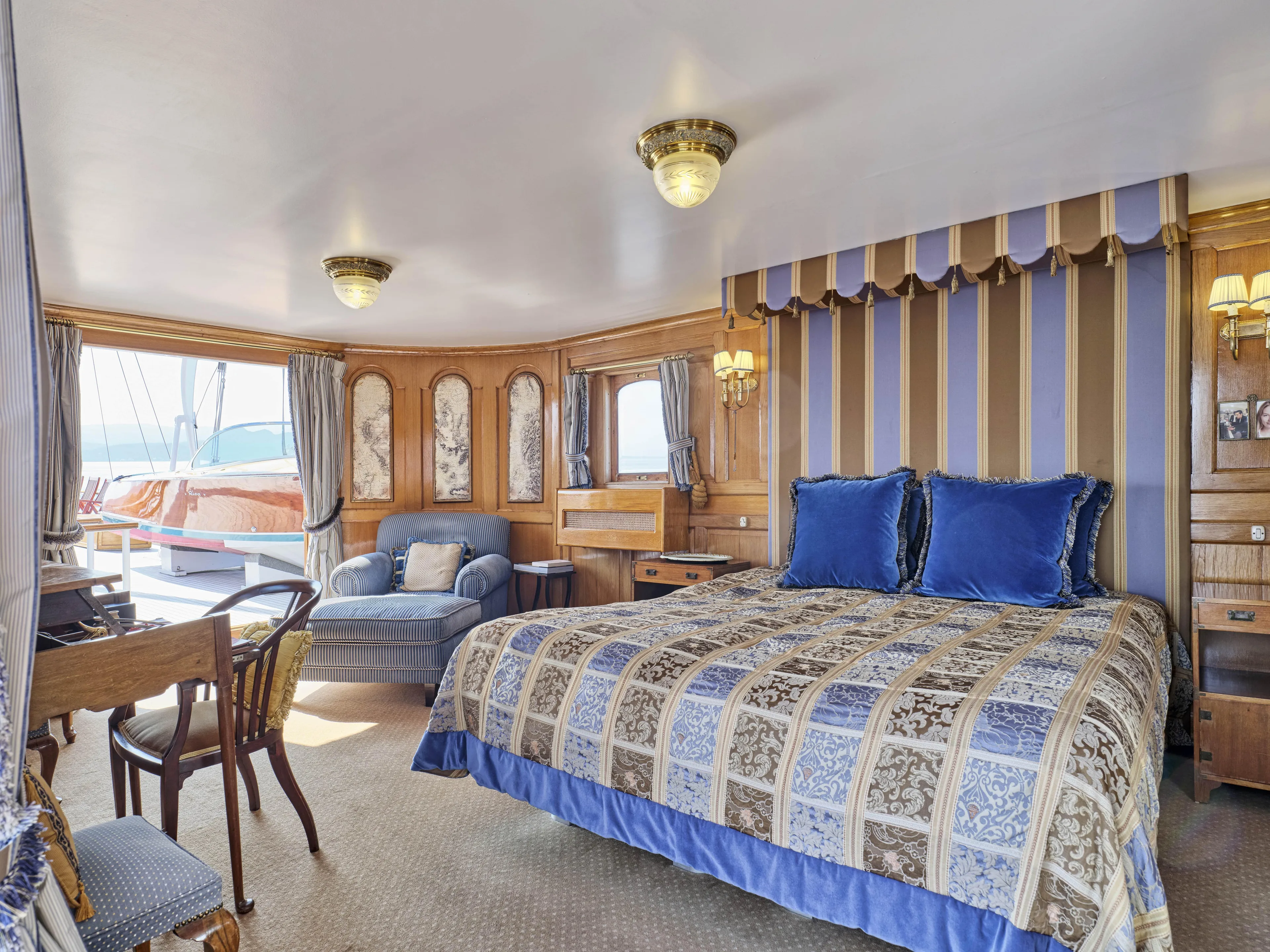 Luxurious ship cabin with elegant decor, featuring a large bed, seating area, and nautical-themed accents.