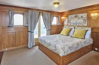 Luxurious ship cabin with wooden paneling, elegant bedding, and nautical decor, built by Ailsa Shipbuilding in 1902.