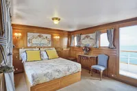 Luxurious ship cabin with wooden decor, ocean view, and elegant furnishings, built by Ailsa Shipbuilding in 1902.