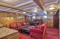 Luxurious ship interior with red seating, wooden paneling, and vintage decor, Ailsa Shipbuilding, 1902.