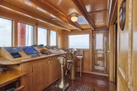 Wooden ship's wheelhouse interior, vintage 1902 Ailsa Shipbuilding, featuring classic navigation instruments.