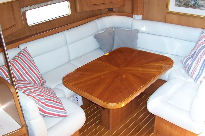 Blue Yacht Photos Pics Luxurious 1994 C&C 51 XL C/B yacht interior with white seating and wooden table.