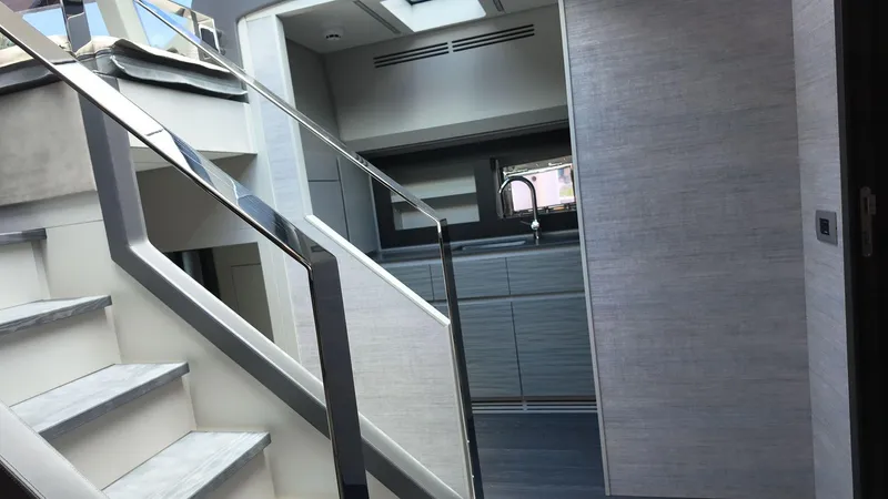 Our Trade Yacht Photos Pics Modern interior of 2022 Pershing 6X yacht with sleek staircase and kitchen area.