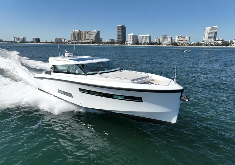  Yacht Photos Pics 2026 Delta Powerboats 48 Coupe cruising on ocean near city skyline.