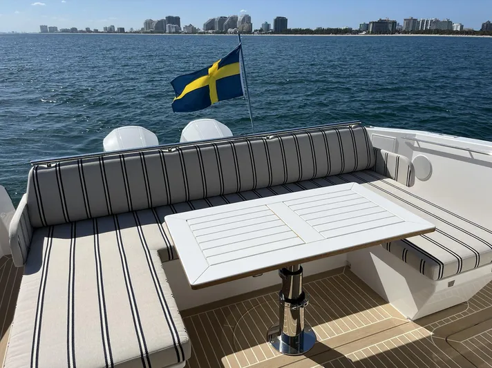  Yacht Photos Pics 2026 Delta Powerboats 48 Coupe deck with seating, table, and Swedish flag, overlooking the ocean.