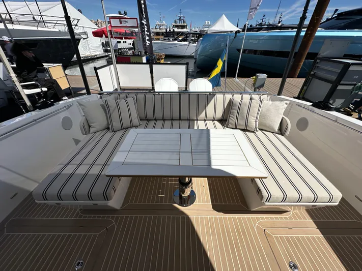  Yacht Photos Pics Luxury seating area on 2026 Delta Powerboats 48 Coupe yacht, featuring striped cushions and table.