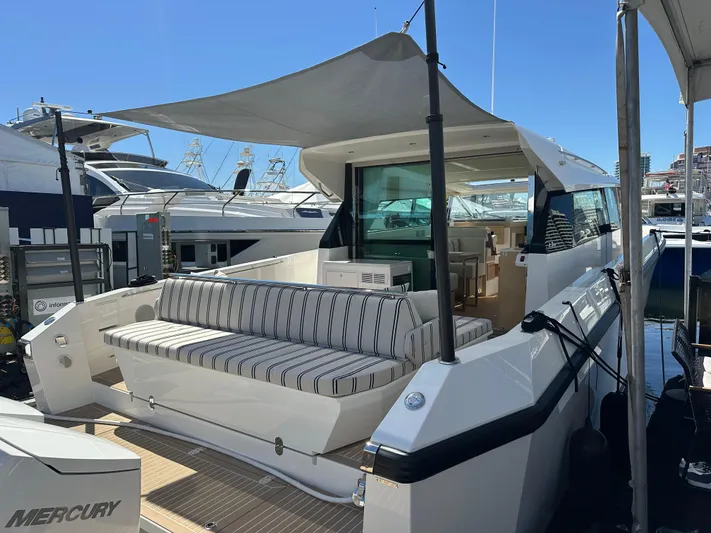  Yacht Photos Pics 2026 Delta Powerboats 48 Coupe with striped seating, docked under a sunshade.