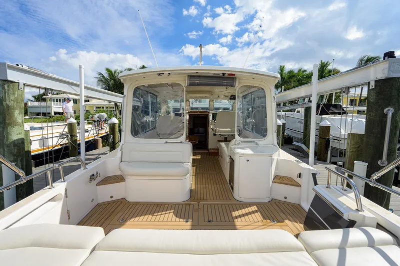 Scout Yacht Photos Pics 2019 MJM 43z yacht interior with white seating and wooden deck, docked under a blue sky.