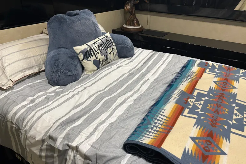  Yacht Photos Pics Cozy bed with striped bedding, plush pillow, and colorful geometric blanket in a Maiora Phantom 1986.