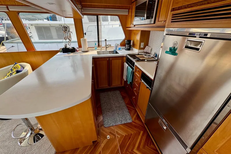 Eagles Soar Yacht Photos Pics Modern kitchen interior on a 2000 Hampton 490 yacht, featuring wood cabinetry and stainless steel appliances.