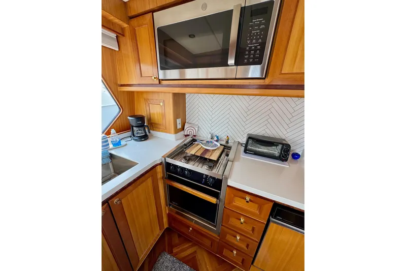 Eagles Soar Yacht Photos Pics Compact kitchen in 2000 Hampton 490 yacht with wooden cabinetry and modern appliances.