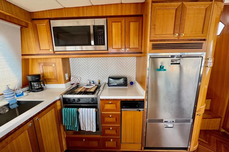Eagles Soar Yacht Photos Pics Wooden yacht kitchen with modern appliances, featuring a microwave, stove, and stainless steel fridge, Hampton 490.