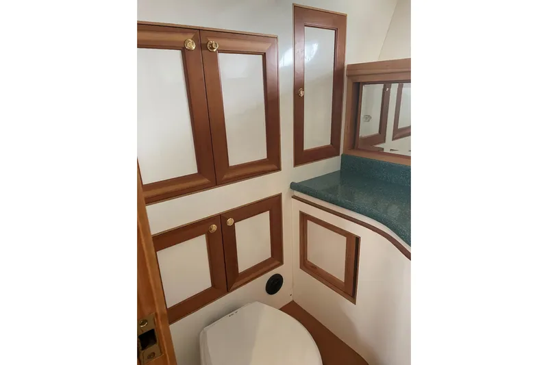 Eagles Soar Yacht Photos Pics Bathroom interior of 2000 Hampton 490 yacht with wooden cabinets and green countertop.