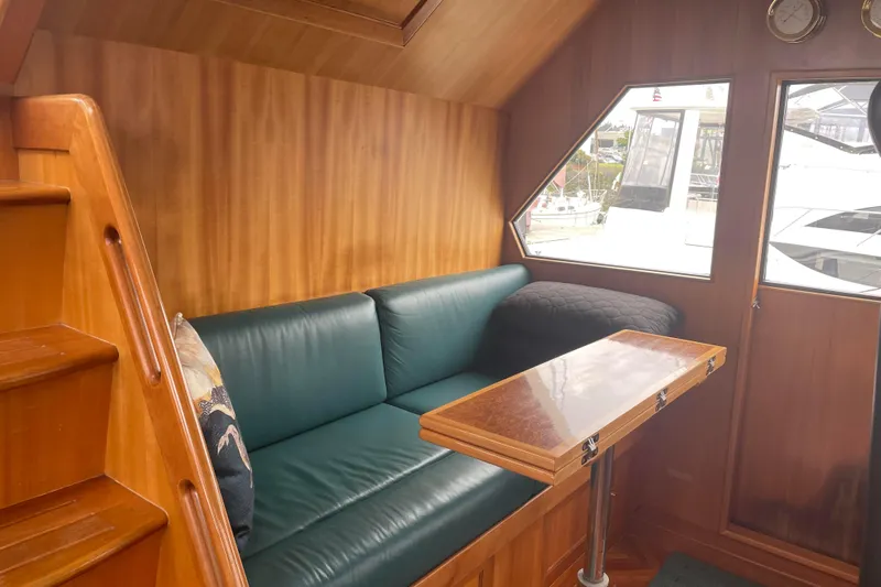 Eagles Soar Yacht Photos Pics Cozy interior of 2000 Hampton 490 yacht with green leather seating and wooden table.