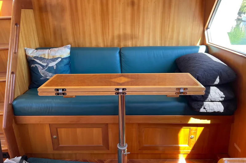 Eagles Soar Yacht Photos Pics Cozy seating area on 2000 Hampton 490 yacht with wooden table and whale-themed pillow.