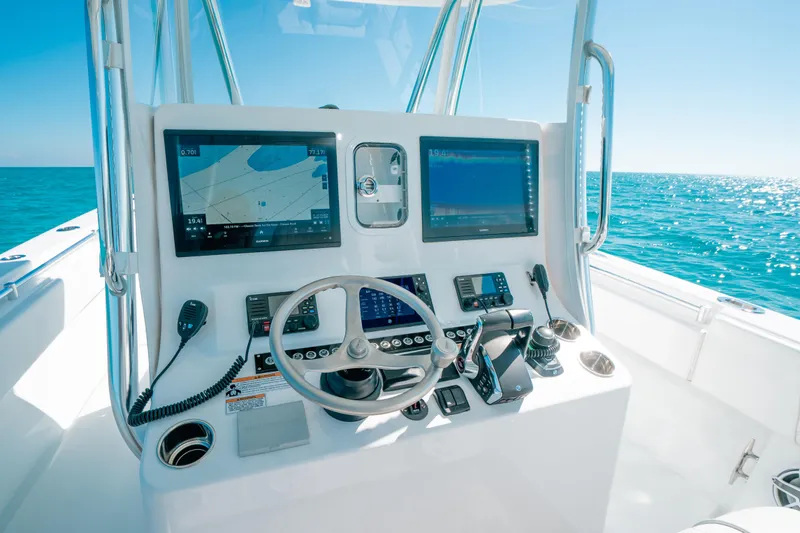  Yacht Photos Pics 2023 Contender 39 ST boat dashboard with navigation screens and controls, set against a clear ocean backdrop.