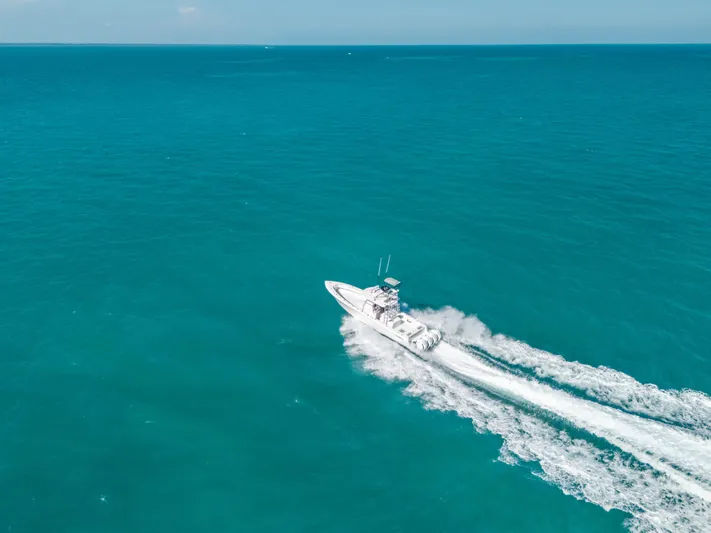 Yacht Photos Pics Aerial view of 2023 Contender 39 ST boat cruising on turquoise ocean waters.