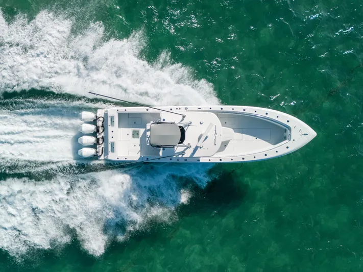  Yacht Photos Pics 2023 Contender 39 ST boat cruising on clear turquoise water, aerial view.