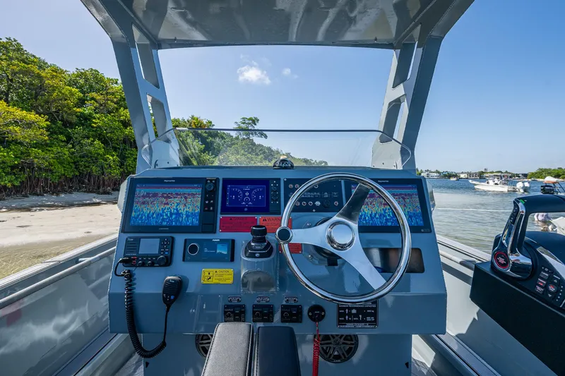  Yacht Photos Pics 2023 SAFE Boats Interceptor dashboard with advanced navigation systems, docked near a scenic shoreline.