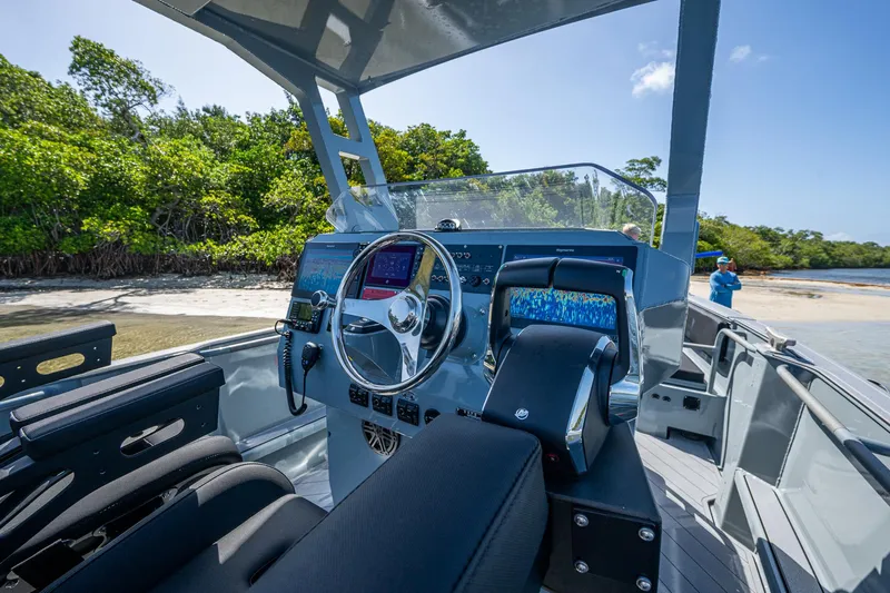  Yacht Photos Pics 2023 SAFE Boats Interceptor cockpit with advanced navigation system, docked near lush shoreline.