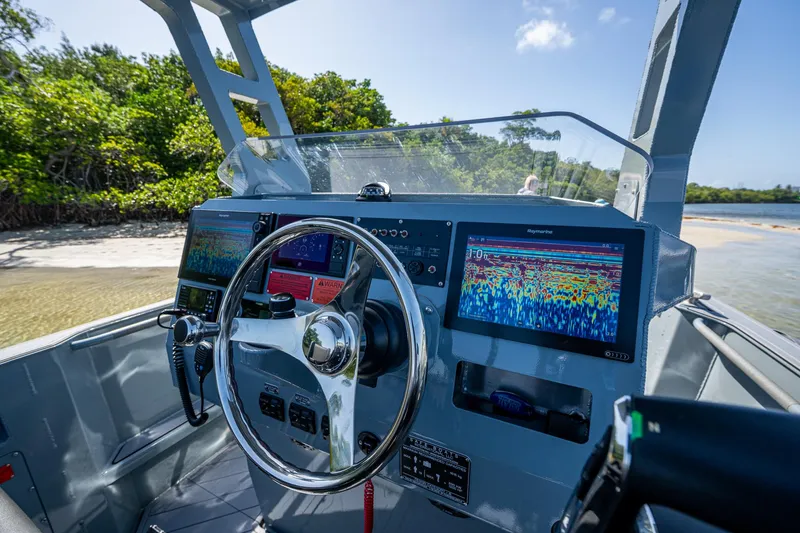  Yacht Photos Pics 2023 SAFE Boats Interceptor dashboard with advanced navigation screens, steering wheel, and coastal background.