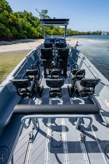  Yacht Photos Pics 2023 SAFE Boats Interceptor with seating, docked near a sandy shore and lush greenery.