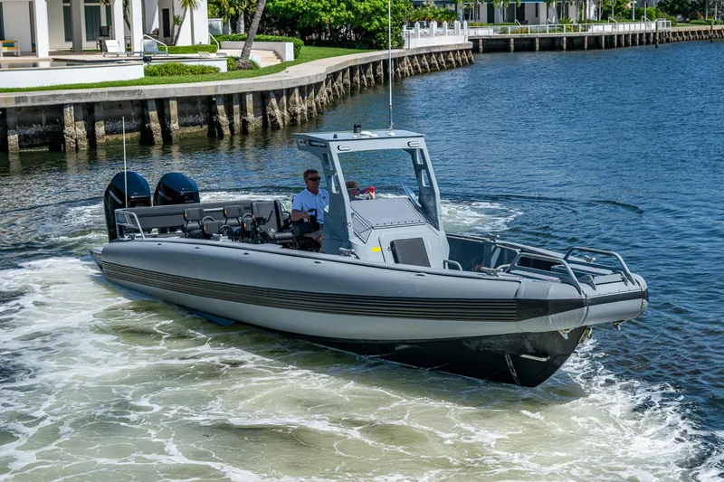  Yacht Photos Pics 2023 SAFE Boats Interceptor navigating a calm waterway near modern waterfront homes.